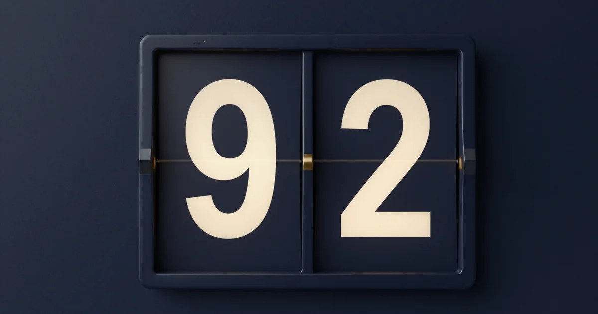 A split-flap display module on a navy wall showing the digits 9 and 2